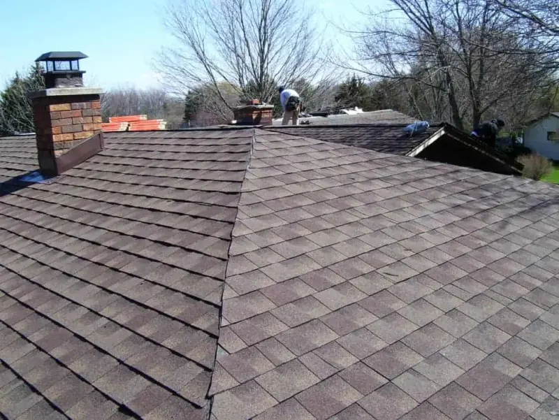 New asphalt shingle roof beside a chimney